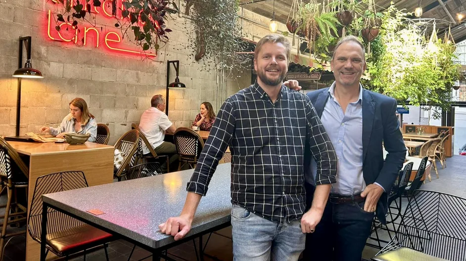 Two members of the Kamal team standing together in a cafe